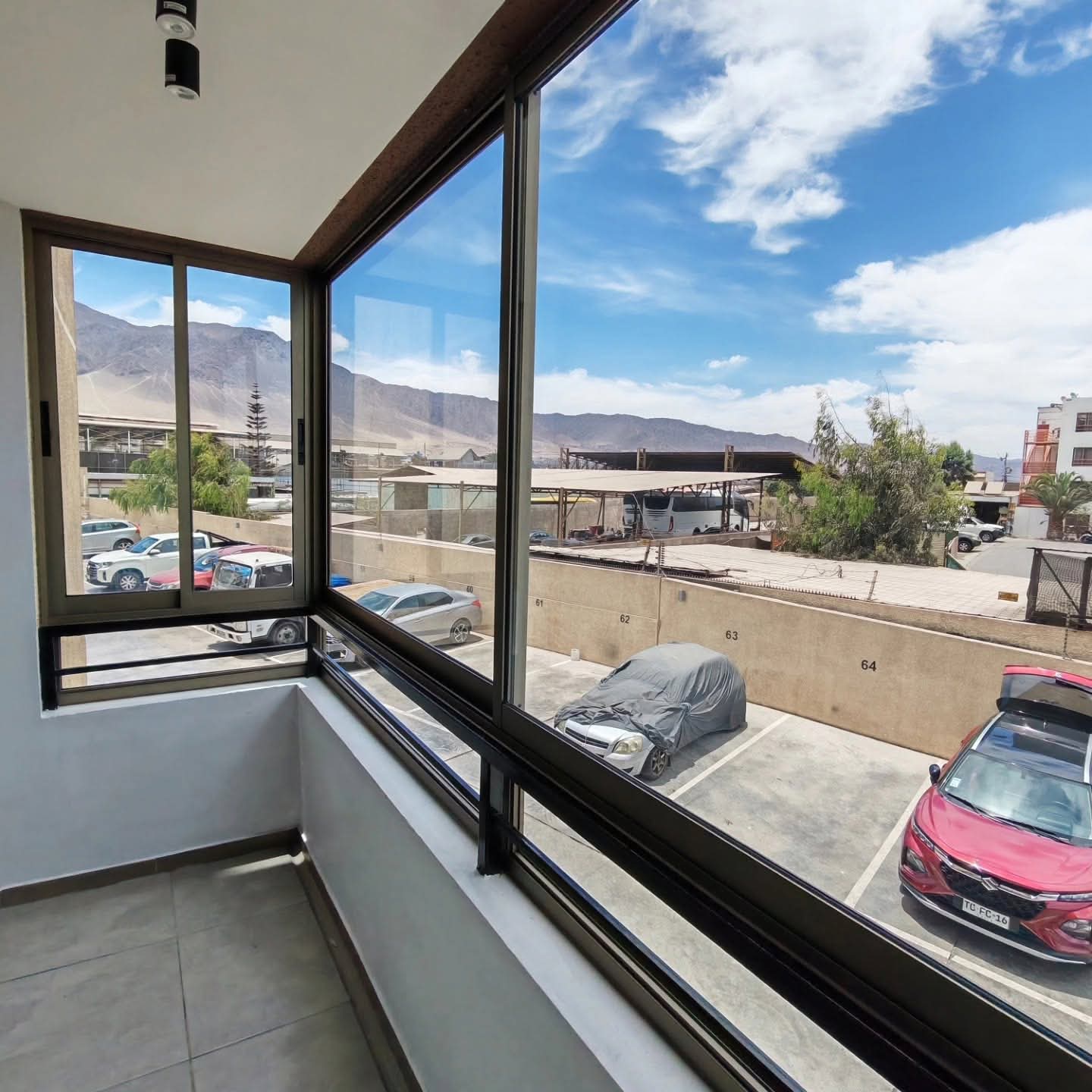 Cierre de balcón en aluminio y vidrio realizado por JCAST en Antofagasta, con vista a la ciudad