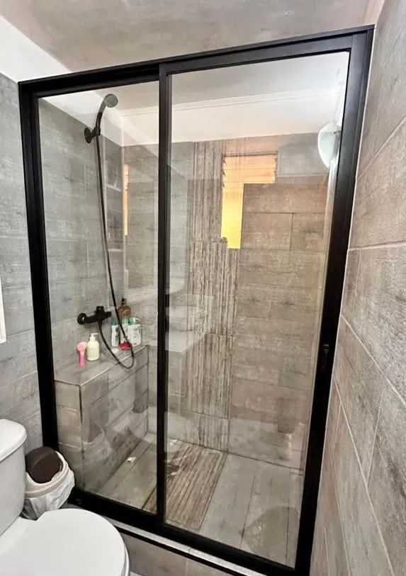 Shower Door de aluminio y vidrio laminado instalado por JCAST en un baño en Antofagasta